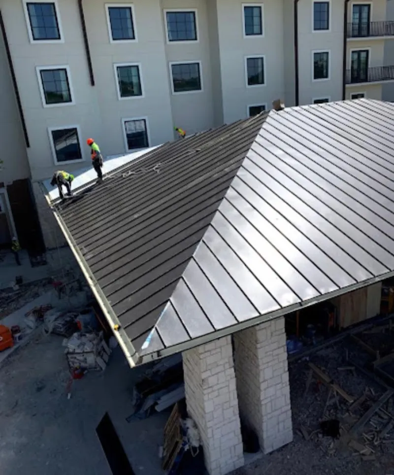 Crew installing standing seam metal roof panels on a commercial project in Northbrook